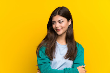 Teenager girl over yellow wall standing and looking to the side