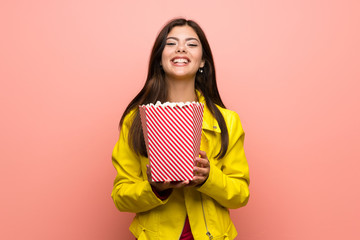 Teenager girl eating popcorns over pink wall