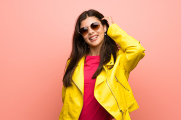 Teenager girl over pink wall with glasses and smiling