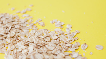 healthy diet, the concept. Grain oatmeal on a Yellow background. Oat flakes scattered