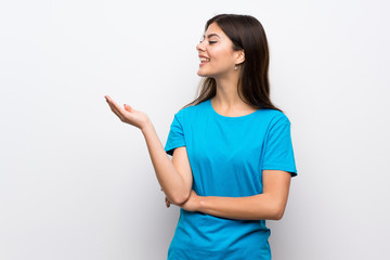 Teenager girl with blue shirt extending hands to the side for inviting to come