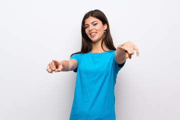 Teenager girl with blue shirt points finger at you while smiling