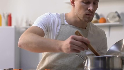 Man trying sauce in pan and screwing up face because of bad taste, cooking