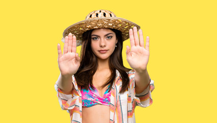 Teenager girl on summer vacation making stop gesture and disappointed over isolated yellow background