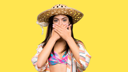 Teenager girl on summer vacation covering mouth with hands over isolated yellow background