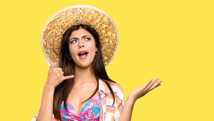 Teenager girl on summer vacation making phone gesture and doubting over isolated yellow background