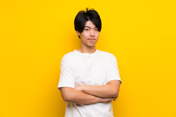 Asian man over isolated yellow wall feeling upset