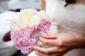 Refined bouquet of white and pink peonies in the hands of an unrecognizable bride