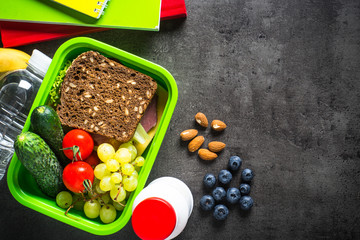 Lunch box with sandwich, fruit, vegetables, water.