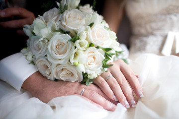 Obraz na płótnie Canvas Exquisite wedding bouquet of white roses and freesia on the hands of newlyweds