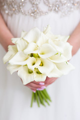 Exquisite wedding bouquet of white callas in the hands of the bride