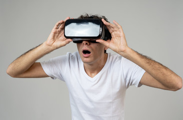 Portrait of cheerful and shocked young man wearing 360 Virtual Reality headset exploring 3D world