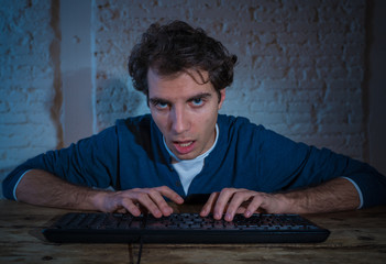 Close up portrait of a overworked and tired young man on computer late at night on moody light.