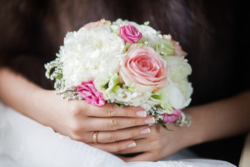 Obraz na płótnie Canvas Beautiful bridal bouquet of peonies and pink roses in the hands of an unrecognizable bride