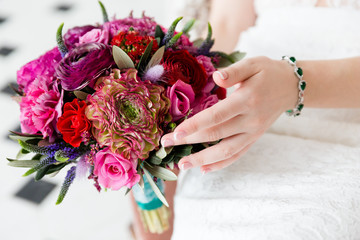 Exquisite bouquet of red and pink roses and peonies in the hands of the bride