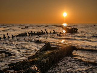 Sunset with a sunken shipwreck from World War II close to the beach