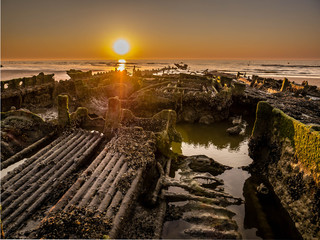 Interior of a sunken shipwreck from World War II close to the beach at sunset