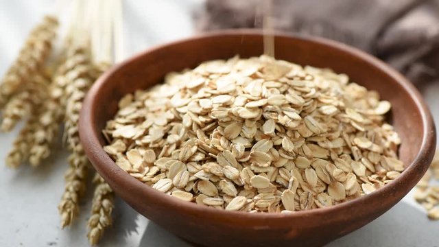 Slow motion of oats or oat flakes falling into bowl. Healthy food, healthy eating, agriculture harvest concept