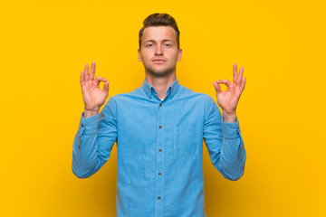 Blonde man over isolated yellow wall in zen pose