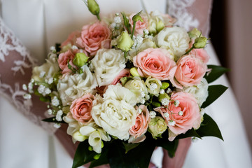 Wedding bouquet of freesia and fuchsia roses in the hands of an unrecognizable bride