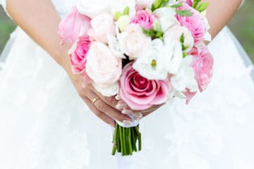 Wedding bouquet of pink roses and white peonies with freesias in the hands of an unrecognizable bride