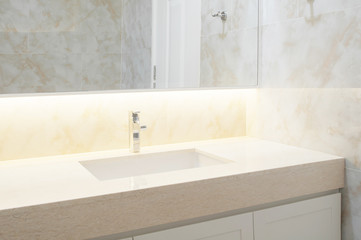 Counter top white,beige marble with washbasin. Wall and floor beige marble stone interior design of restroom or toilet background. Restroom clean design with accessories background. Selective focus.