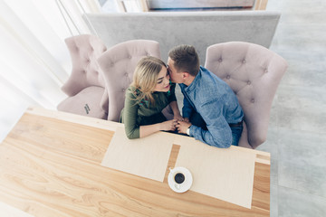 man and woman drink coffe, smiling and kissing  in cafe with stylish interior. Together forever. Loving Couple on the date in restaurant. love story concept indoor