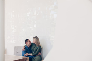 happy couples in a beautiful restaurant. man and woman and stylish white room. hugs of a loving couple indoor in the stylish interior.Attractive man and woman іs smiling and  hugging each other