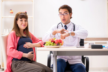 Pregnant woman visiting doctor discussing healthy diet