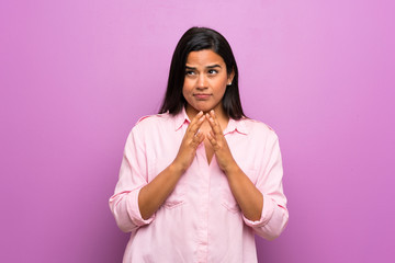 Young Colombian girl over purple wall scheming something
