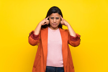 Young Colombian girl over yellow wall having doubts and thinking