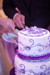 Beautiful wedding three-tier cake decorated with flowers. Bride and groom Cutting cake. Lavender color.