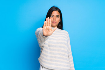 Young Colombian girl with sweater making stop gesture denying a situation that thinks wrong