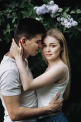 Fototapeta premium A romantic couple in love hugging in front of a flowering bush