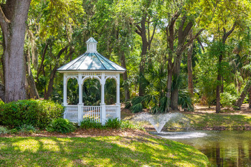 A White Gazebo on the shore of a lake under live oak trees