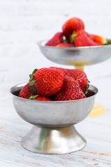 Bright ripe strawberry in a metal cups on a light background.
