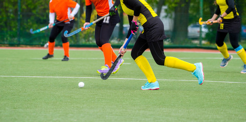 three women battle for control of ball during field hockey game