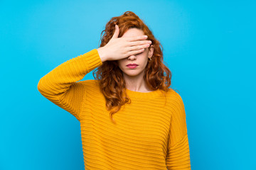 Redhead woman with yellow sweater covering eyes by hands. Do not want to see something