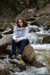 Young woman sitting on a rock in the middle of the river