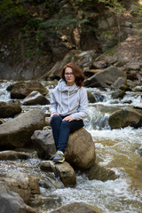 Young woman sitting on a rock in the middle of the river