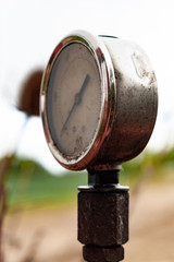 old rusty manometer on abandoned red agriculture machine in the field