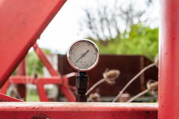 old rusty manometer on abandoned red agriculture machine in the field