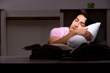 Obraz premium Male handsome student preparing for exams late at home 