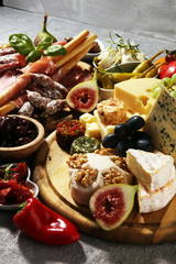 Italian antipasti wine snacks set. Cheese variety, Mediterranean olives, crudo, Prosciutto di Parma, salami and wine in glasses over grunge background.