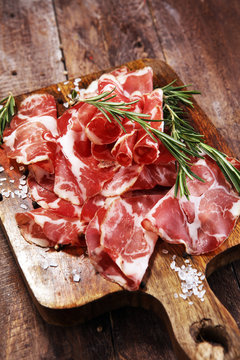 Italian sliced cured coppa with spices. Raw ham. Crudo or jamon with rosemary