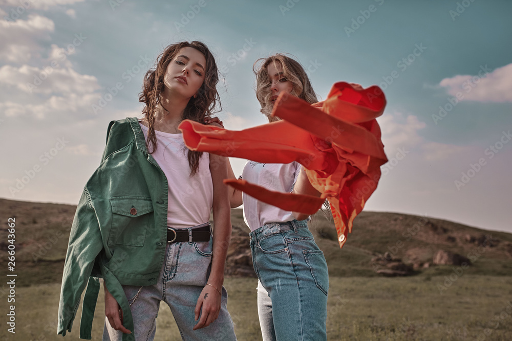 Wall mural high fashion portrait of two stylish beautiful woman in trendy jackets and jeans posing outdoor. vog