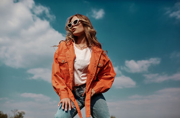 High fashion portrait of stylish beautiful woman in trendy jackets and jeans posing outdoor. Vogue style. - obrazy, fototapety, plakaty