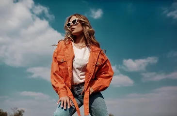 High fashion portrait of stylish beautiful woman in trendy jackets and jeans posing outdoor. Vogue style. © svitlychnaja