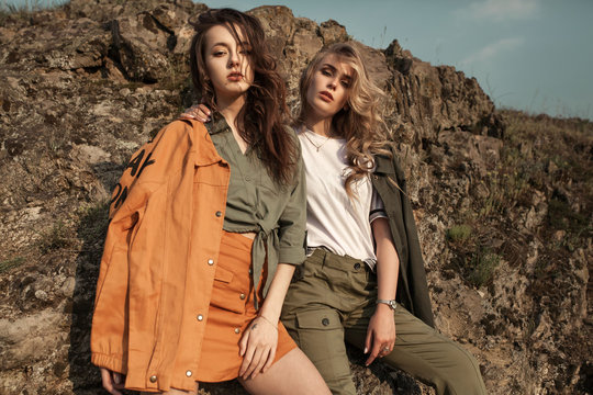 High fashion portrait of two stylish beautiful woman in trendy jackets and jeans posing outdoor. Vogue style.