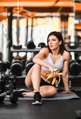 Fototapeta premium Young sporty woman has a break in training in the gym. makes a snack banana.